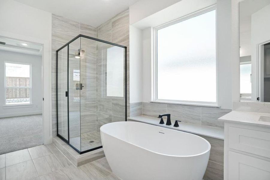 Bathroom featuring vanity, independent shower and bath, and tile walls