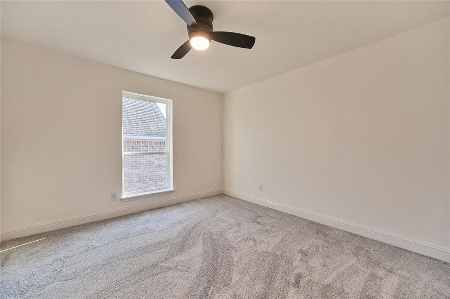 Carpeted spare room featuring ceiling fan