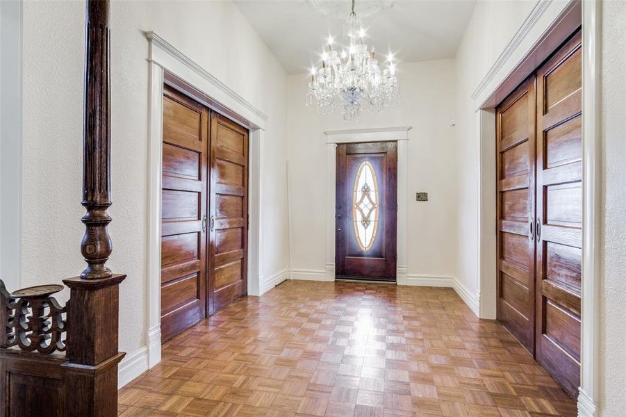 Foyer with light parquet floors and a chandelier