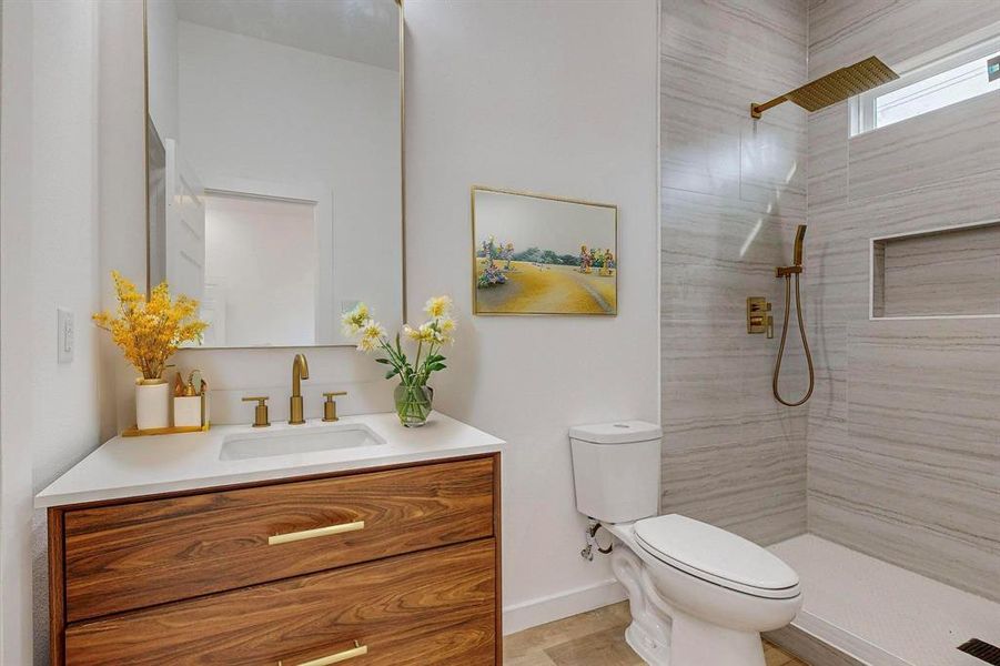 Bathroom with tiled shower, vanity, and toilet