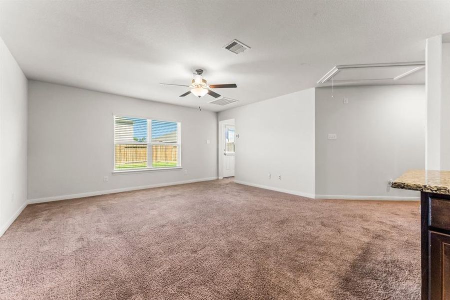 The Family room features lush carpeting, double windows, and lighted ceiling fan. There is also a convenient rear access to the backyard close by.