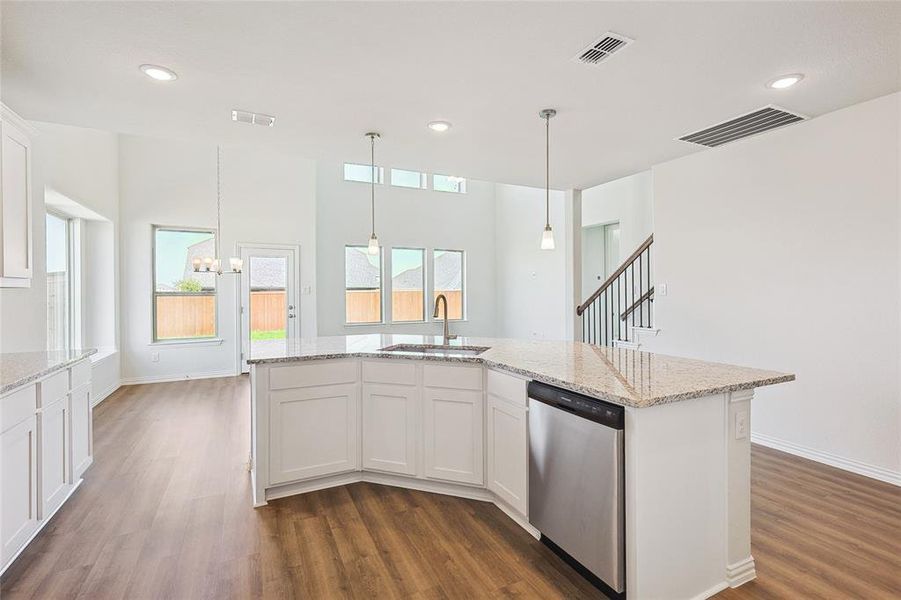 Kitchen with white cabinets, dark hardwood / wood-style flooring, an inviting chandelier, stainless steel dishwasher, and sink