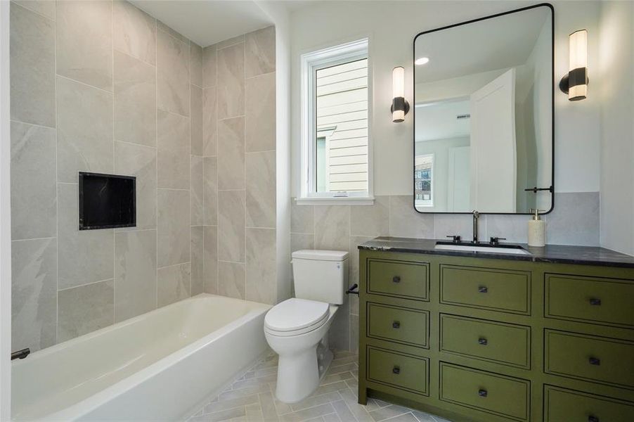 This modern, sleek bathroom features a bathtub, toilet, olive vanity, and tile floor. One of the 4 full bathrooms in the home.