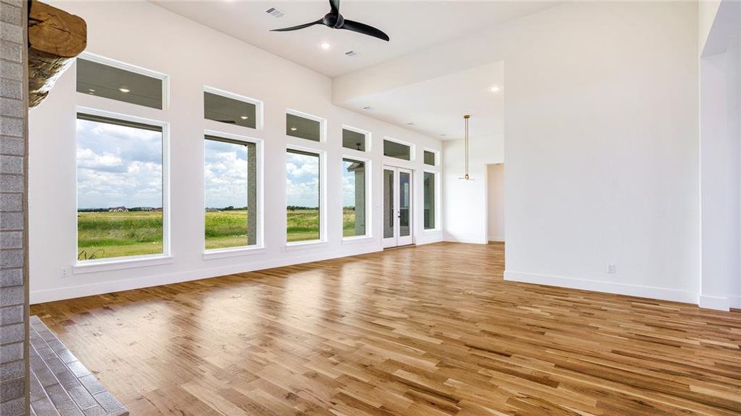 Empty room with hardwood / wood-style flooring, plenty of natural light, and ceiling fan