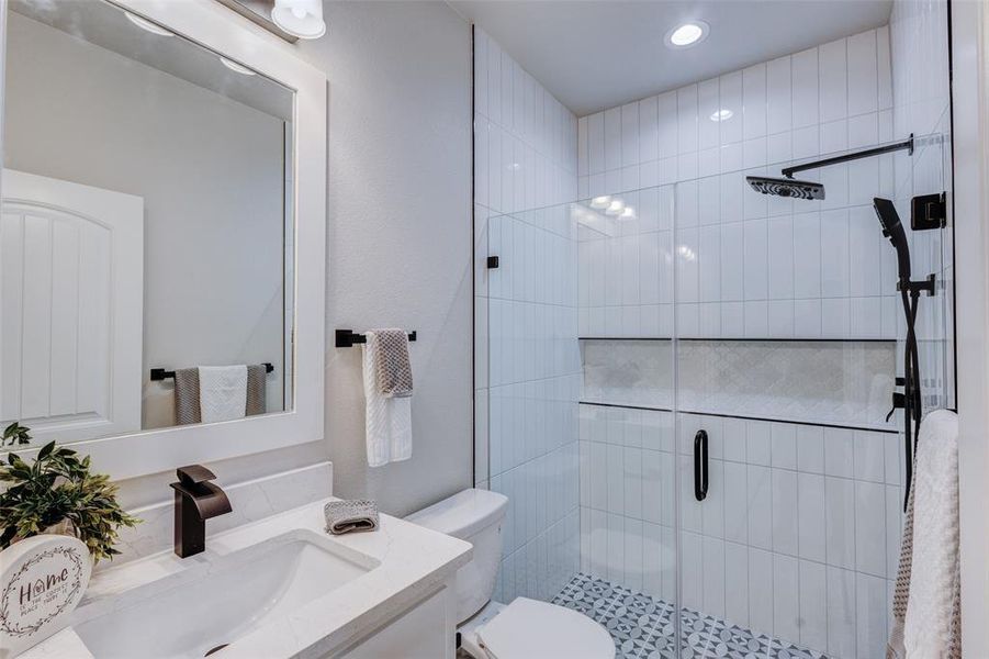 Bathroom featuring vanity, a shower with shower door, and toilet