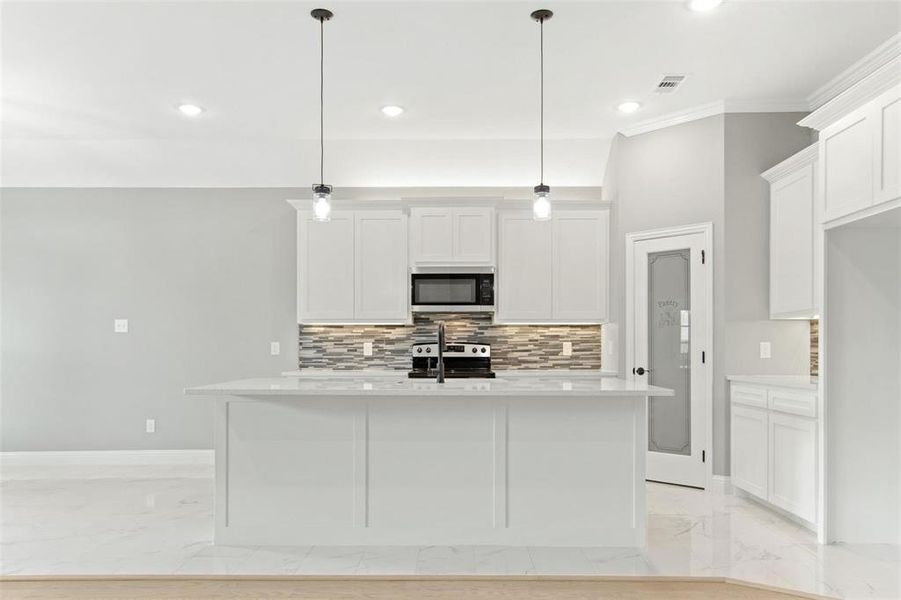 Kitchen featuring an island with sink, hanging light fixtures, and stainless steel appliances