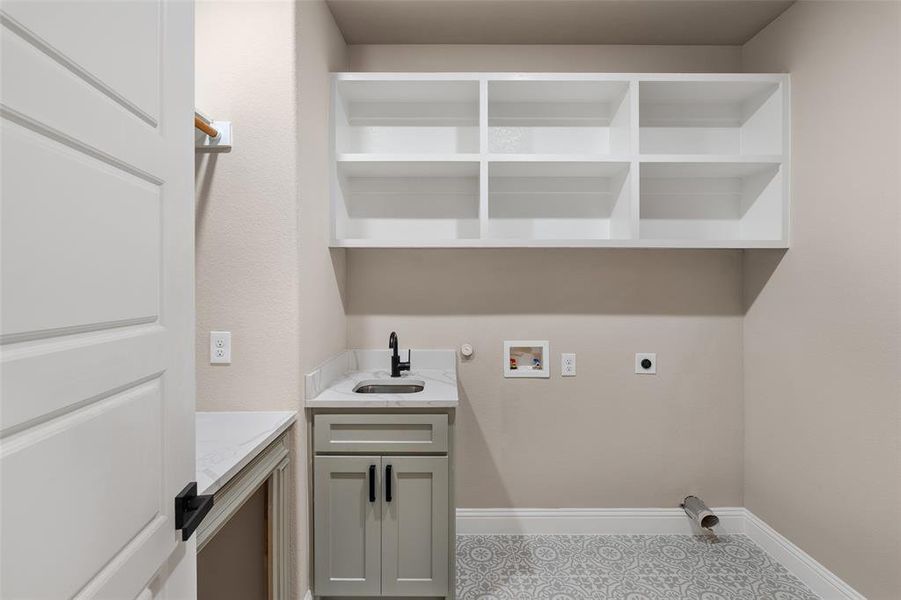 Washroom with cabinets, electric dryer hookup, tile floors, hookup for a washing machine, and sink