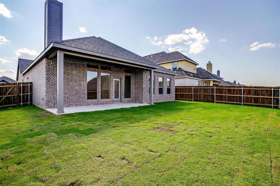 Rear view of property featuring a lawn and a patio