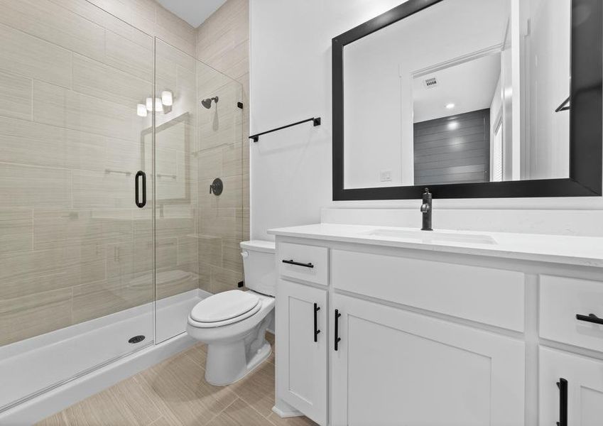 The secondary bathroom has a large vanity and glass, walk-in shower.