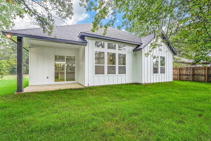 Rear view of property featuring a lawn and a patio area