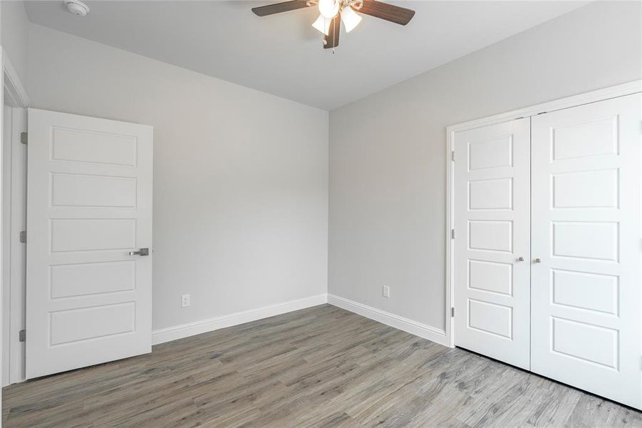 Unfurnished bedroom featuring light wood-type flooring, a closet, and ceiling fan