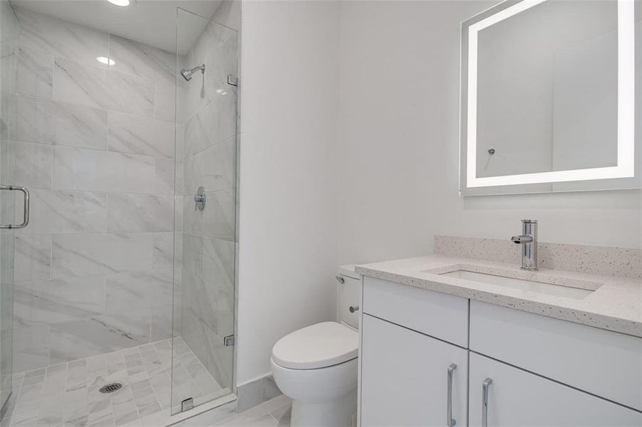 Bathroom featuring walk in shower, vanity, and toilet