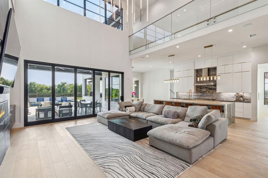 Living room with light wood-type flooring, a high ceiling, and plenty of natural light