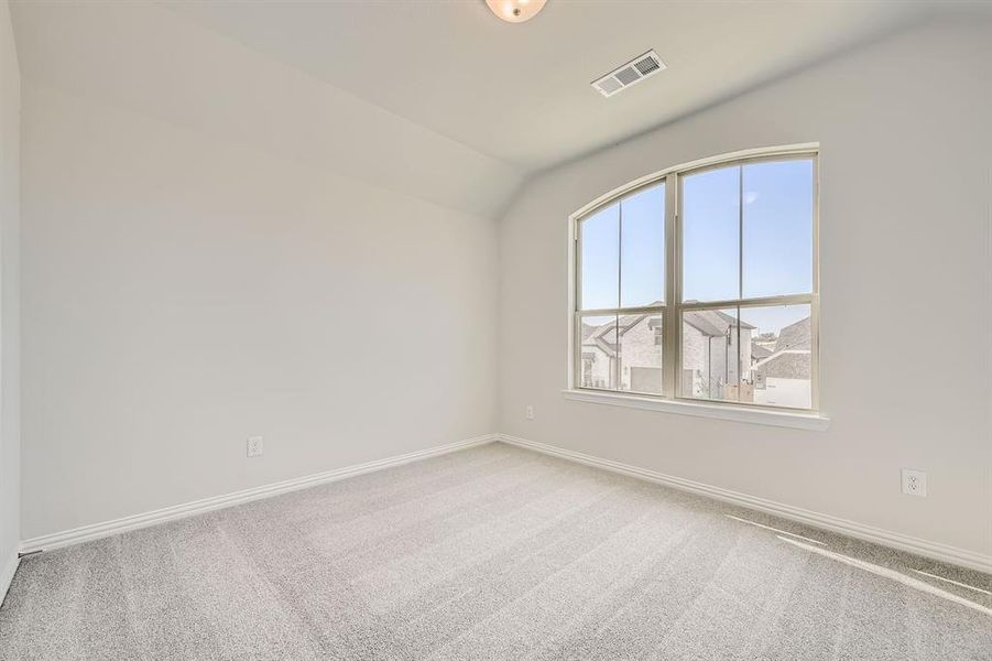 Carpeted spare room with vaulted ceiling