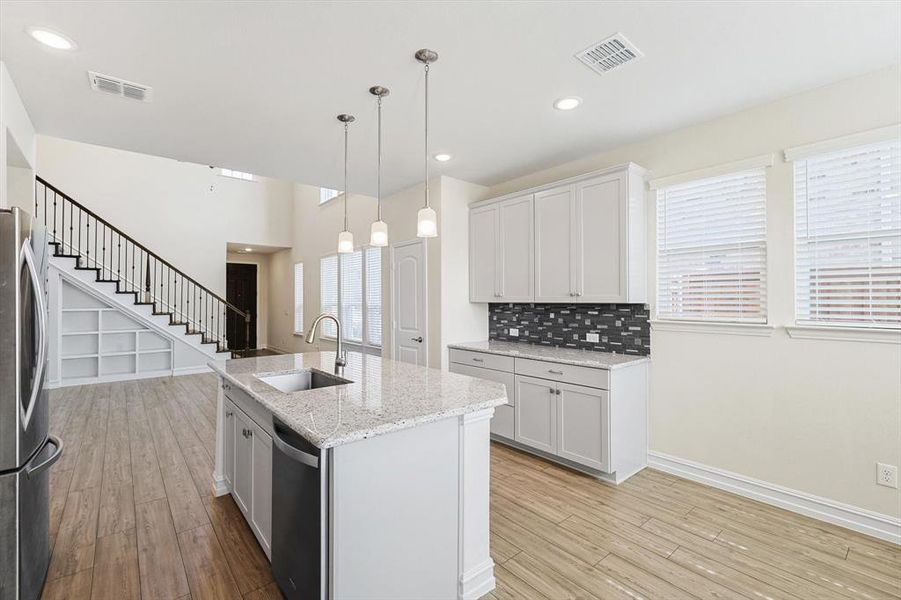 Kitchen featuring white cabinetry, sink, an island with sink, and stainless steel appliances