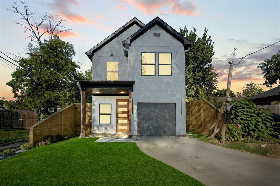 Modern home featuring a garage and a lawn