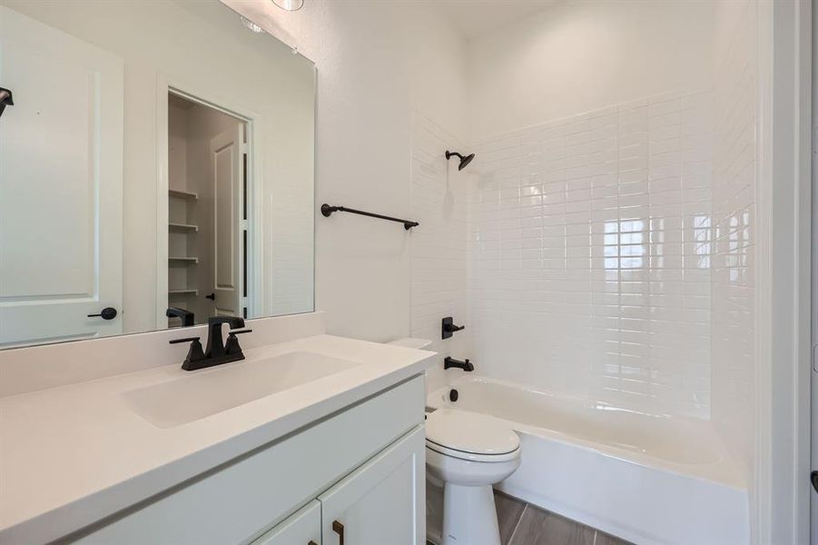 Full bathroom featuring hardwood / wood-style floors, toilet, tiled shower / bath combo, and vanity