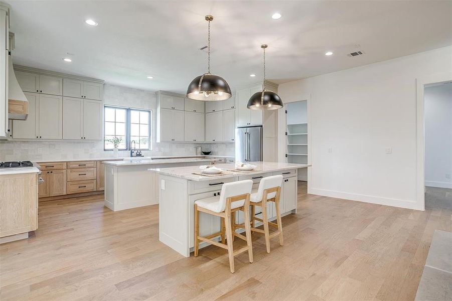 Kitchen with light hardwood / wood-style flooring, a center island, sink, and pendant lighting