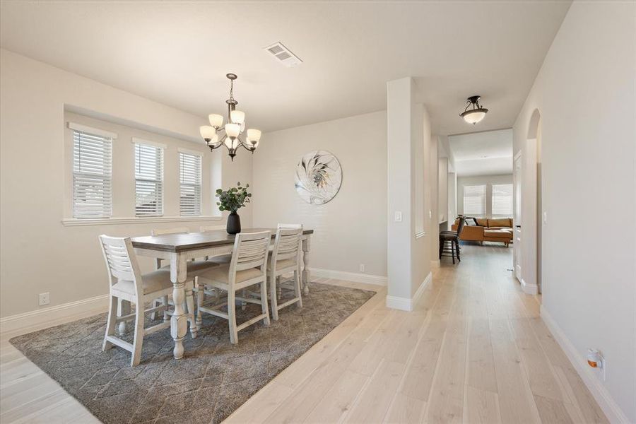 The formal dining space features an inviting bronze chandelier and ample natural light. Engineered wood floors. Neutral paint palette.