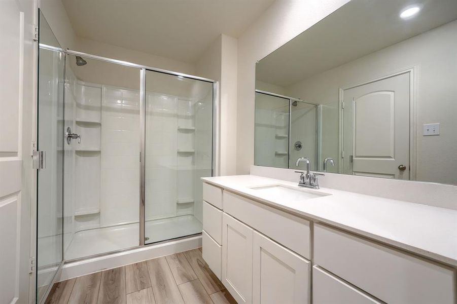 Bathroom featuring vanity, hardwood / wood-style floors, and a shower with door