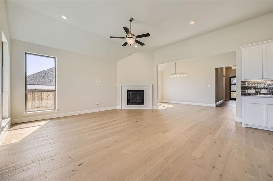 Unfurnished living room featuring lofted ceiling, light hardwood / wood-style floors, and ceiling fan