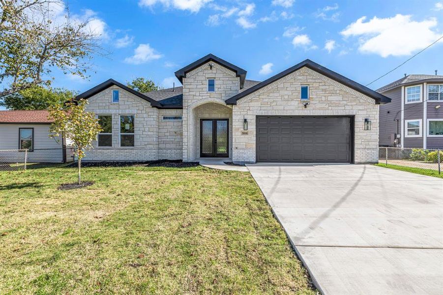 View of front of house featuring french doors, a front yard, and a garage