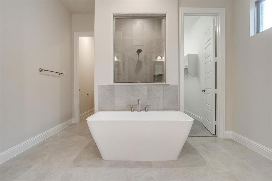 Bathroom with tile patterned flooring, a bathtub, and tile walls