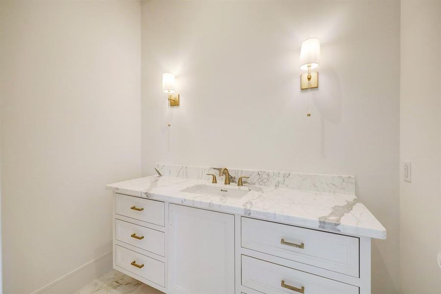 This convenient powder bath with beautiful marble countertop and sconce lighting services the first floor and is located near the entryway.