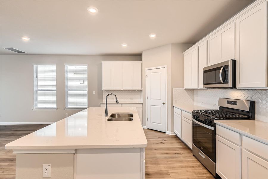 The kitchen comes ready to use with sleek quartz countertops and stainless steel Whirlpool appliances including a gas range, microwave, and dishwasher.