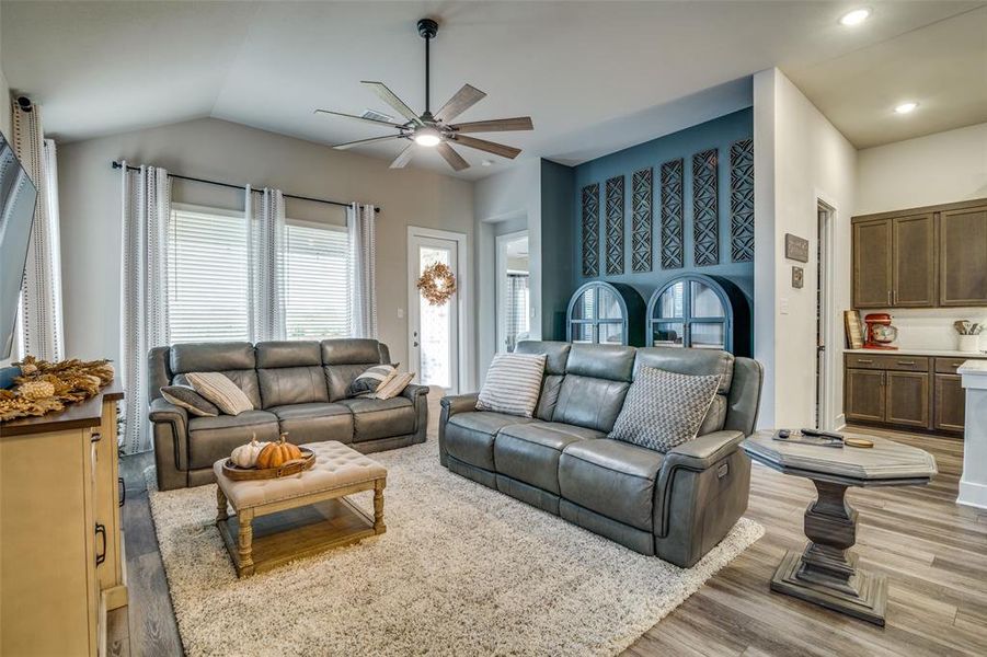 Living room with light wood-type flooring, lofted ceiling, and ceiling fan