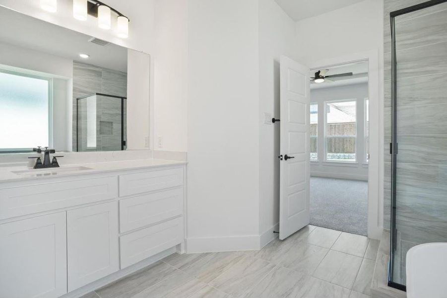 Bathroom with vanity, a shower with shower door, and ceiling fan