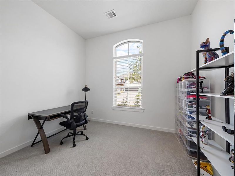 Welcome to the charming secondary bedroom (1 of 3) located at the front of the home. This inviting space is bathed in natural light, featuring an arched window that offers picturesque views of the surrounding neighborhood.