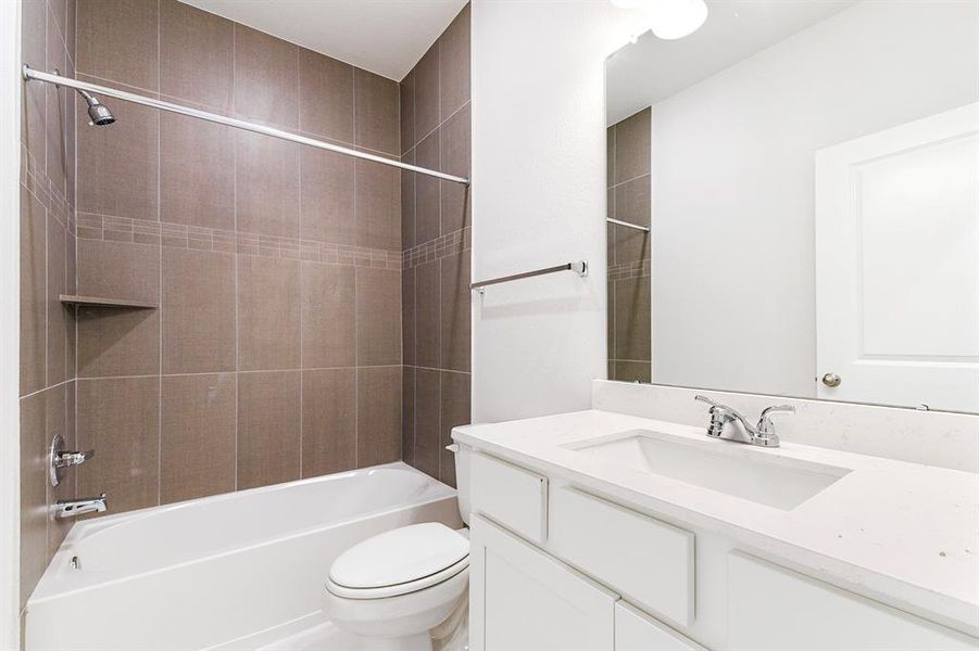 Secondary bathroom with quartz countertops, white cabinets and shower/tub w/textured tile.