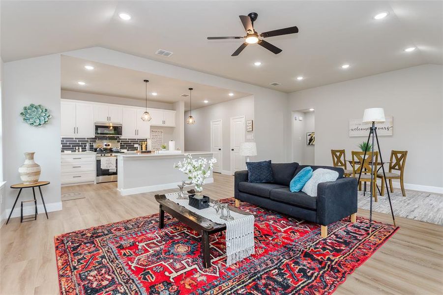 Living room featuring light hardwood / wood-style floors, lofted ceiling, and ceiling fan