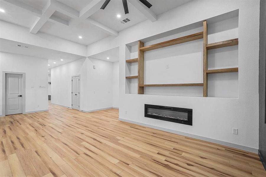 Unfurnished living room with ceiling fan, beamed ceiling, and wood-type flooring