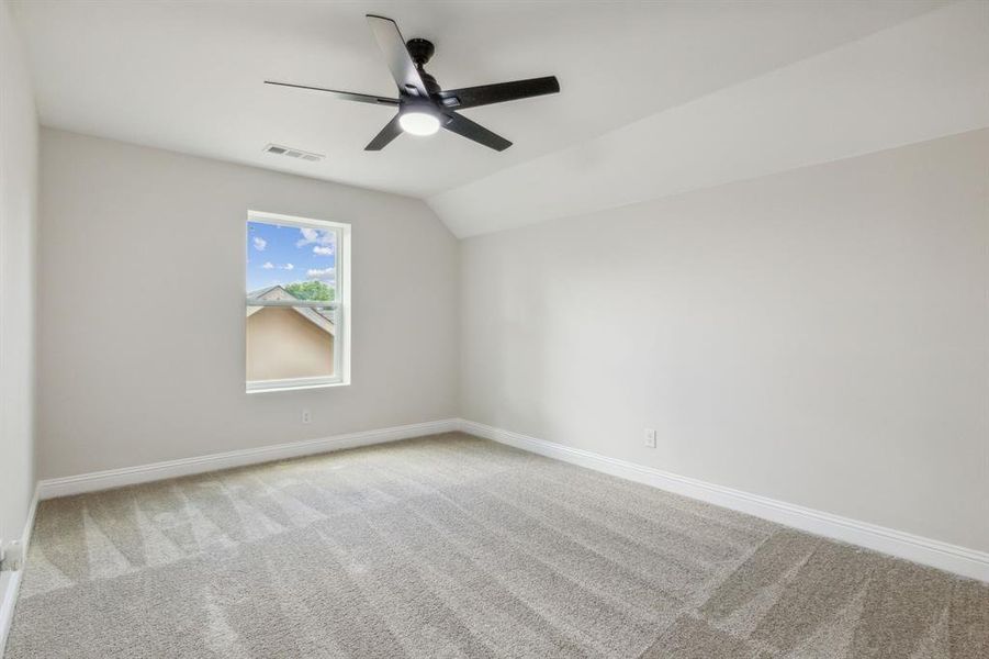 Carpeted spare room with vaulted ceiling and ceiling fan