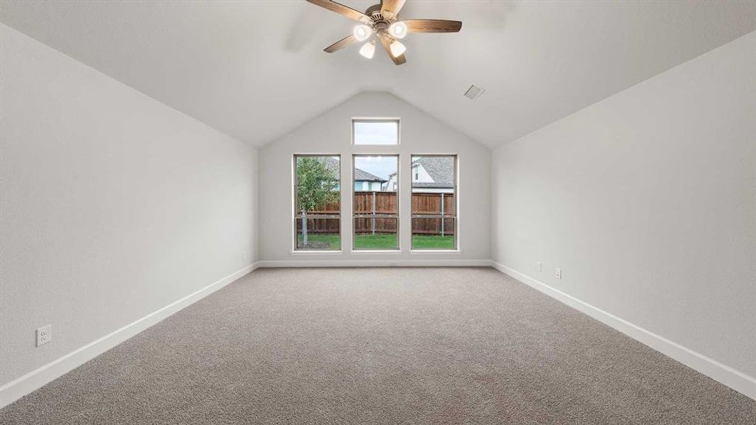 Carpeted spare room featuring lofted ceiling and ceiling fan