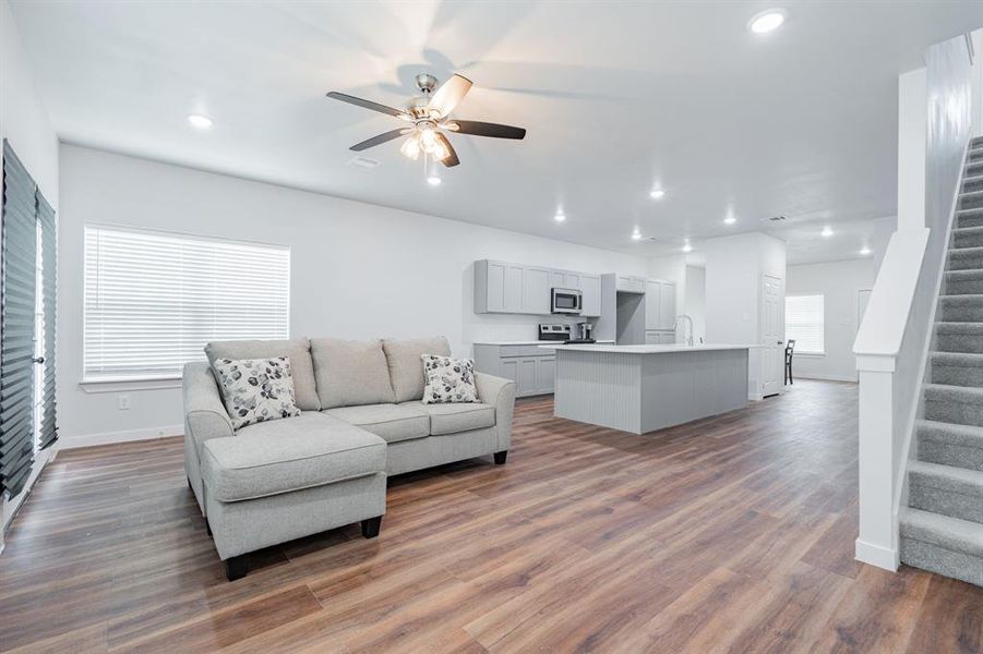 Living room featuring ceiling fan, sink, and wood-type flooring