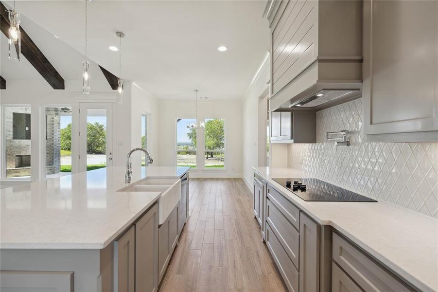 Kitchen featuring pendant lighting, custom exhaust hood, a wealth of natural light, and black electric cooktop