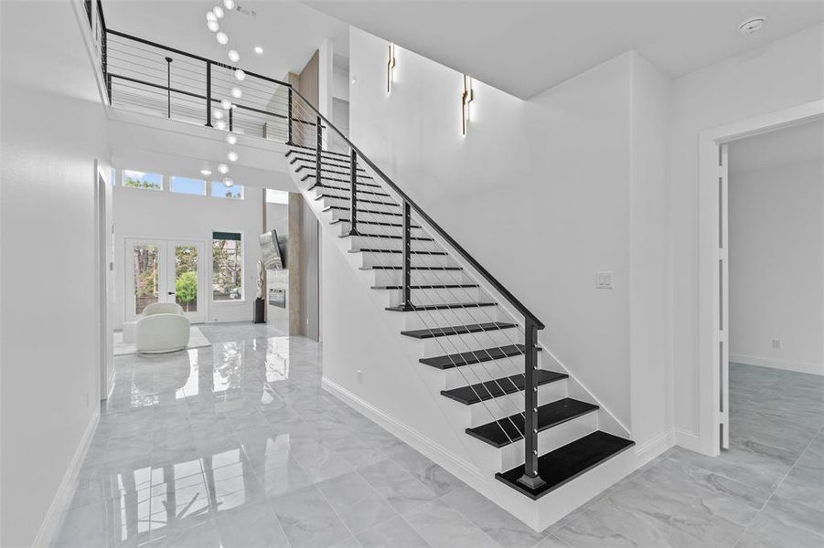 Staircase with french doors and a high ceiling