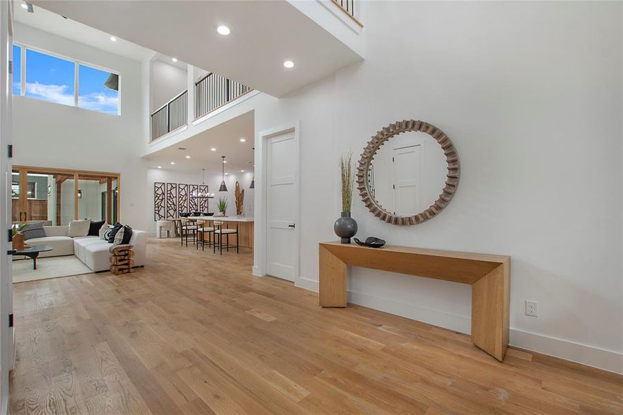 Hallway featuring a high ceiling and light hardwood / wood-style floors