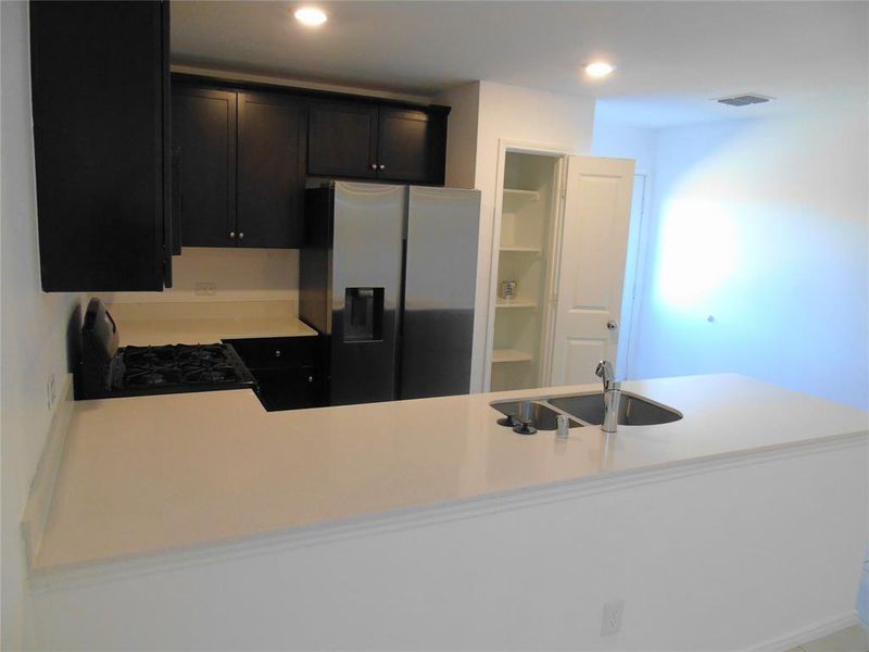 Kitchen featuring kitchen peninsula, black range with gas stovetop, sink, and stainless steel fridge with ice dispenser