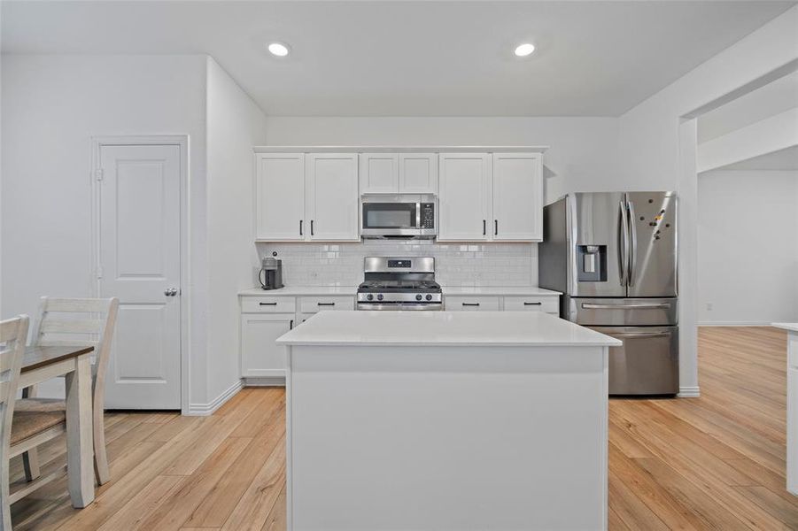 Kitchen with light hardwood / wood-style flooring, white cabinetry, and stainless steel appliances