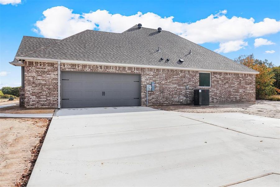 View of front of home with a garage and central AC