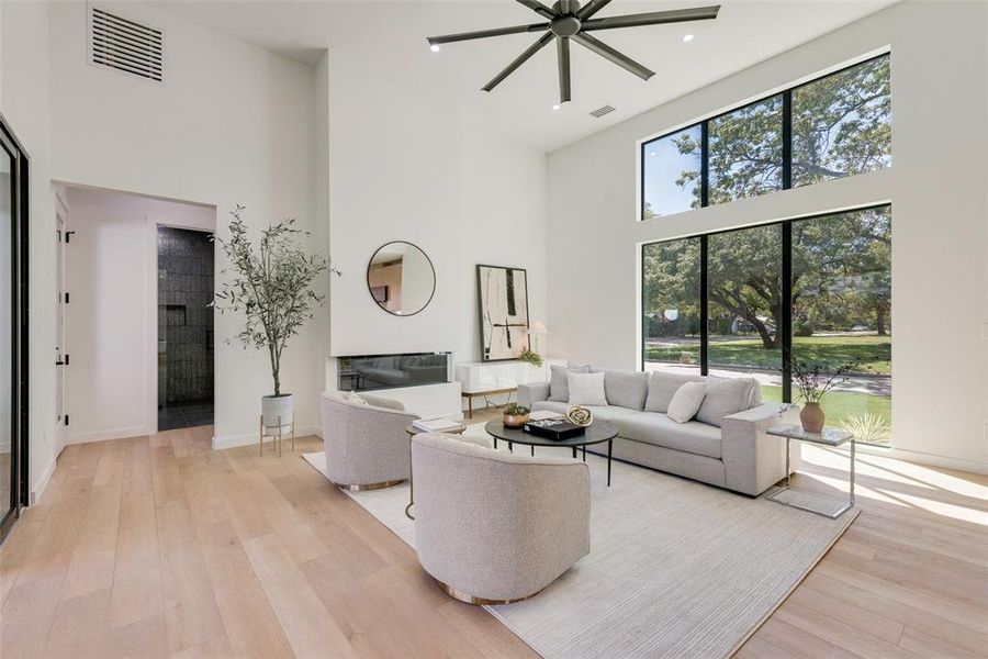 Living room featuring light hardwood / wood-style flooring, a high ceiling, ceiling fan, and a healthy amount of sunlight