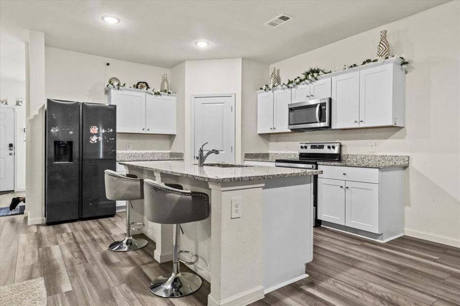 Kitchen with white cabinetry, sink, a kitchen island with sink, dark wood-type flooring, and stainless steel appliances