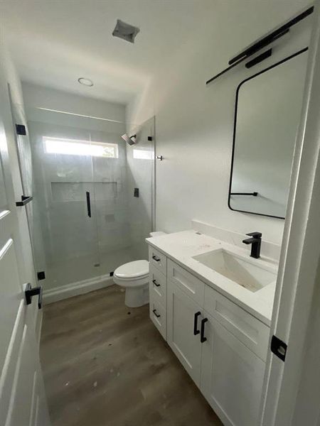 Bathroom featuring vanity, toilet, walk in shower, and hardwood / wood-style floors