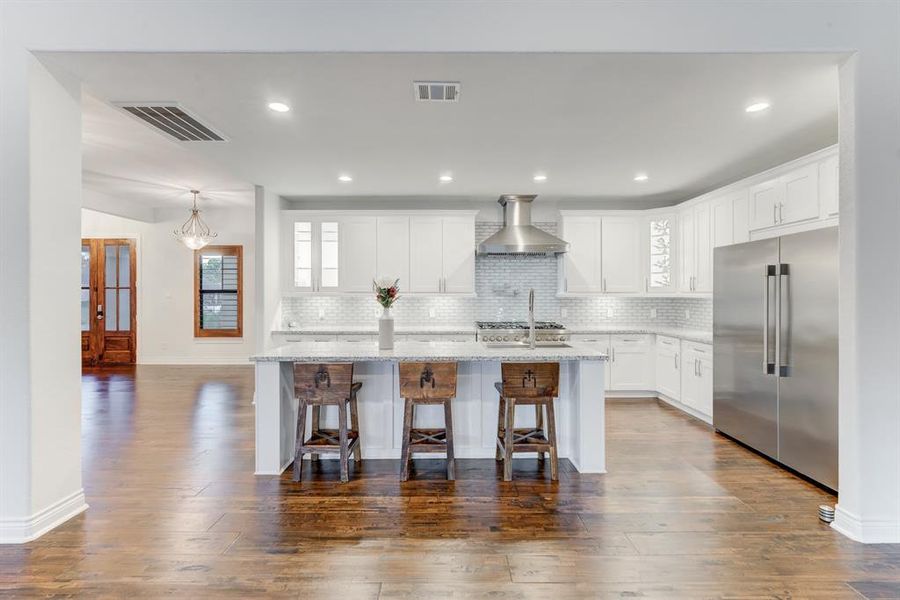 Noticing the great flow created by the central island with bar seating. The room is well-lit with natural light and recessed lights.