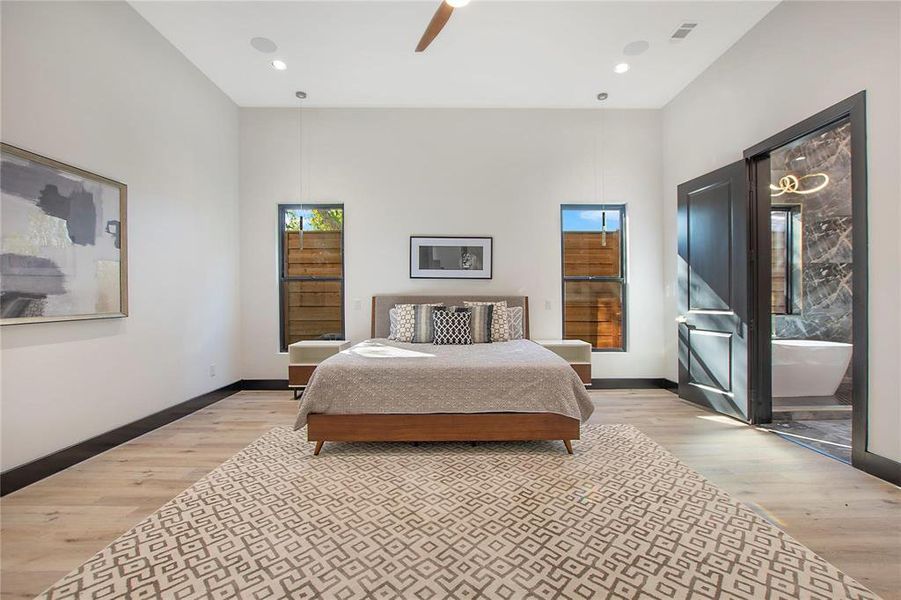 Bedroom featuring light hardwood / wood-style floors, ceiling fan, and a towering ceiling