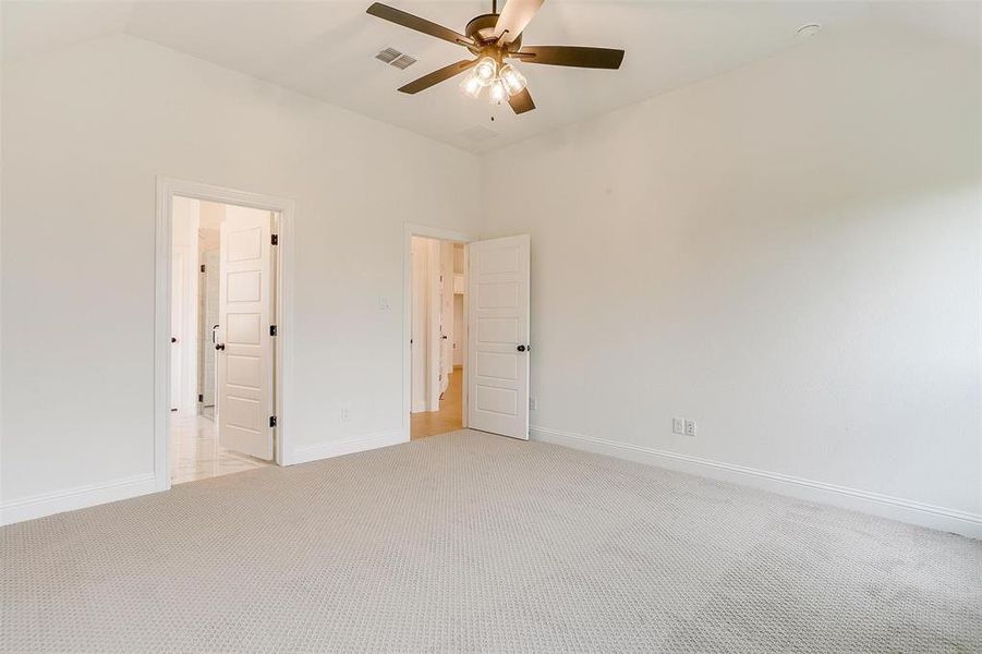 Unfurnished bedroom featuring lofted ceiling, ceiling fan, and light carpet